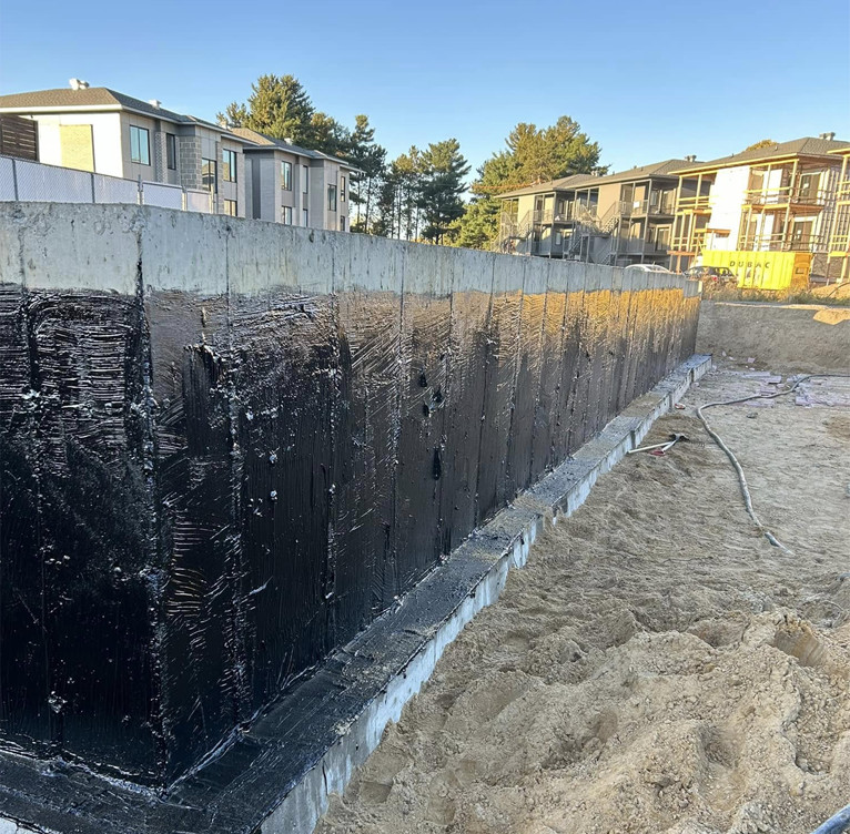 Foundation waterproofing with the application of a waterproofing coating to the concrete wall.